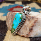 Deltoid-shaped sterling silver pendant featuring Sonoran Gold turquoise with vivid blue-green tones and natural golden matrix, handcrafted by Navajo artist Artie Yellowhorse.  Side view.
