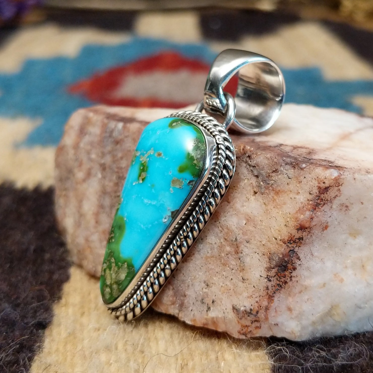 Deltoid-shaped sterling silver pendant featuring Sonoran Gold turquoise with vivid blue-green tones and natural golden matrix, handcrafted by Navajo artist Artie Yellowhorse.  Side view.
