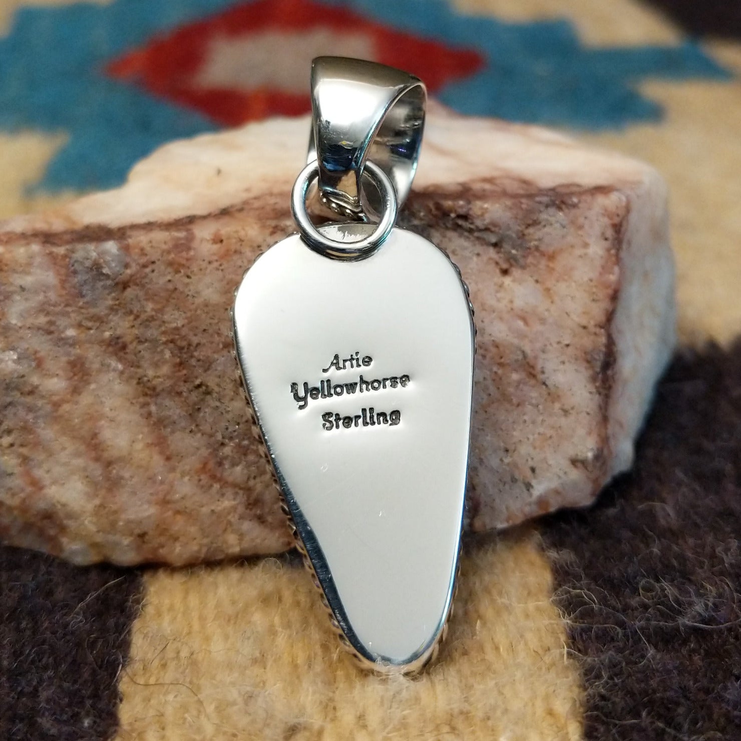 Deltoid-shaped sterling silver pendant featuring Sonoran Gold turquoise with vivid blue-green tones and natural golden matrix, handcrafted by Navajo artist Artie Yellowhorse.  Back view with artisan and silver stamp.