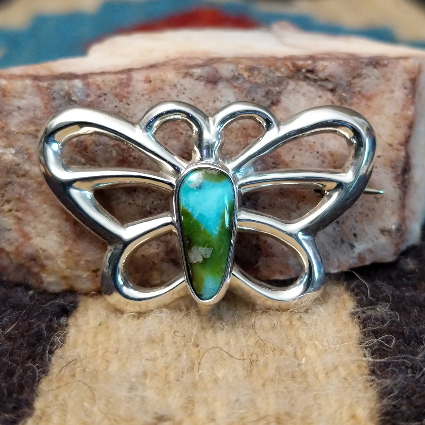 Sterling silver butterfly pin featuring Sonoran Gold turquoise stones with blue-green hues and natural golden matrix, handcrafted by Native American artist Francis Jones.  Front view.