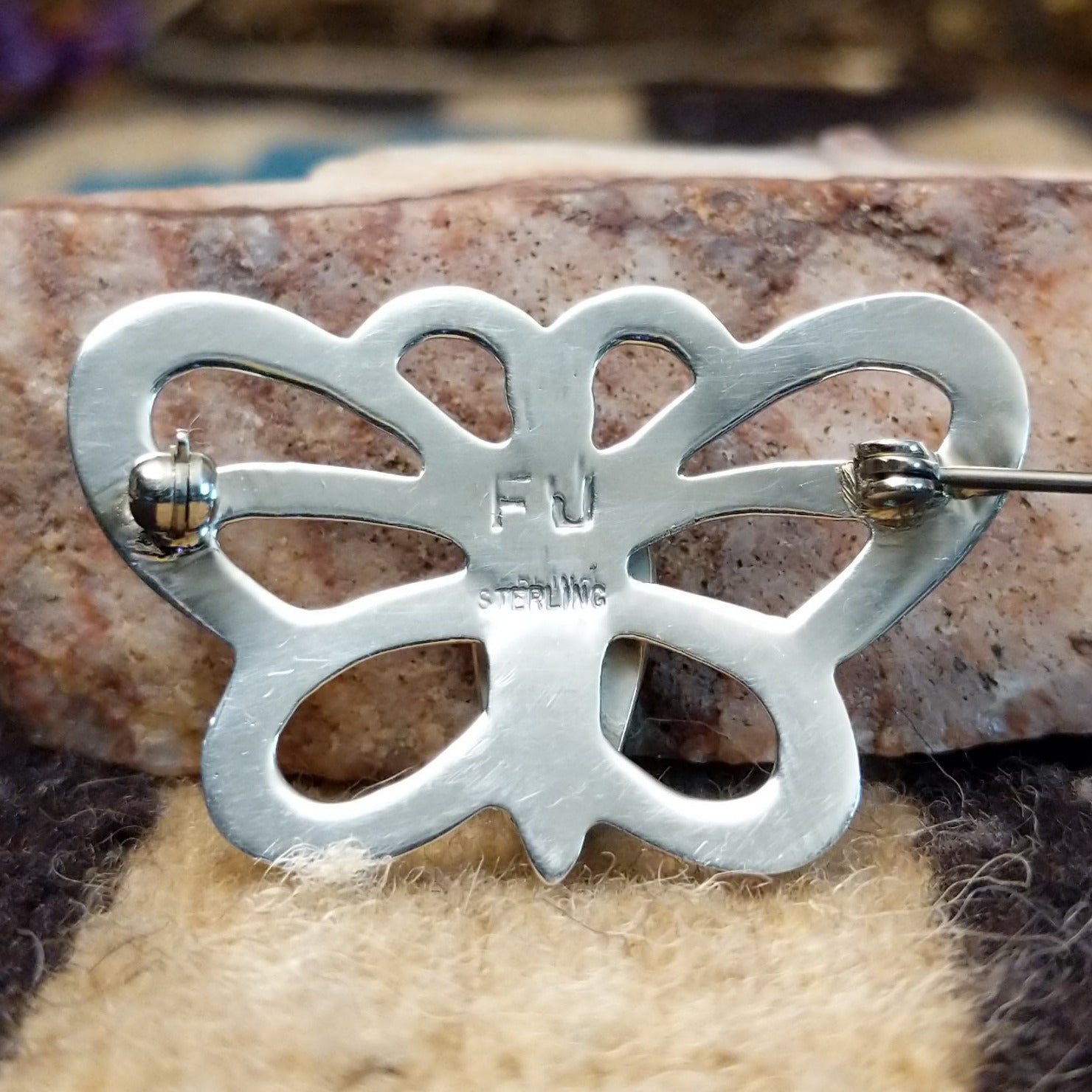 Sterling silver butterfly pin featuring Sonoran Gold turquoise stones with blue-green hues and natural golden matrix, handcrafted by Native American artist Francis Jones.  Back view with artisan and silver stamp.