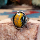 Navajo sterling silver ring with an oval Bumblebee Jasper stone featuring bold yellow, orange, black, and cream natural patterns.  Front view.