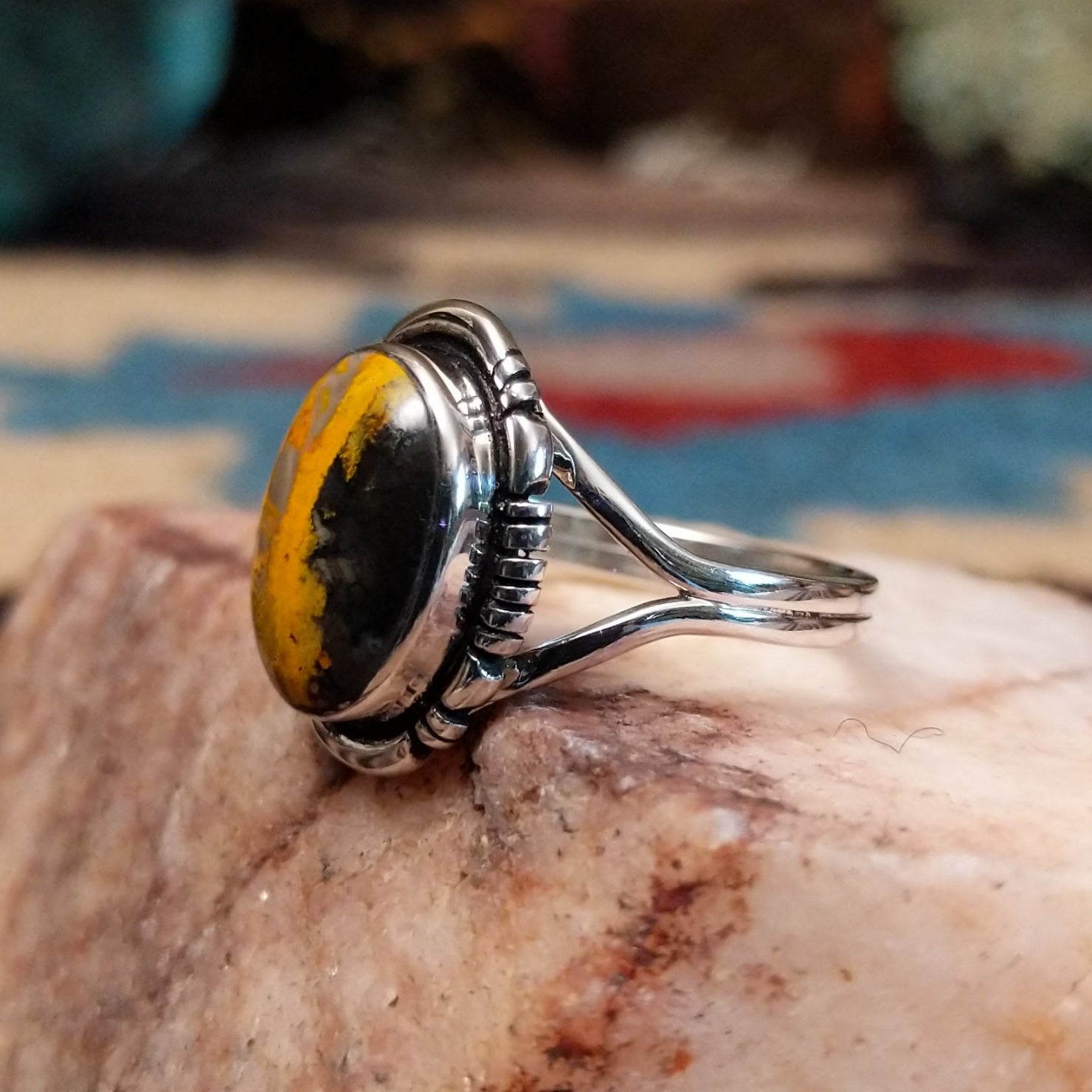 Navajo sterling silver ring with an oval Bumblebee Jasper stone featuring bold yellow, orange, black, and cream natural patterns.  Side view.