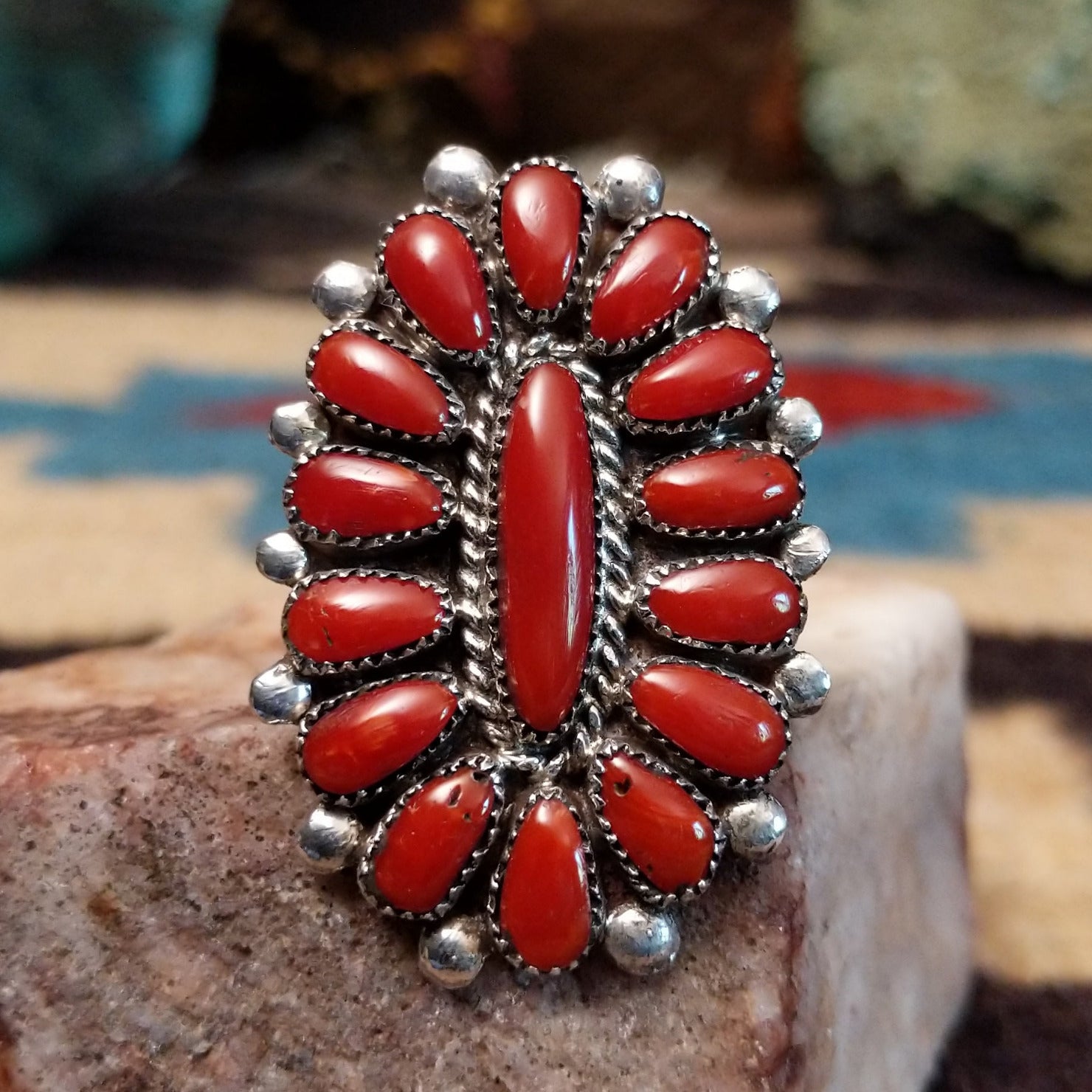 Sterling silver floral coral ring by Lorraine Waatsa featuring a vibrant red coral stone in a detailed Southwestern design.  Front view.