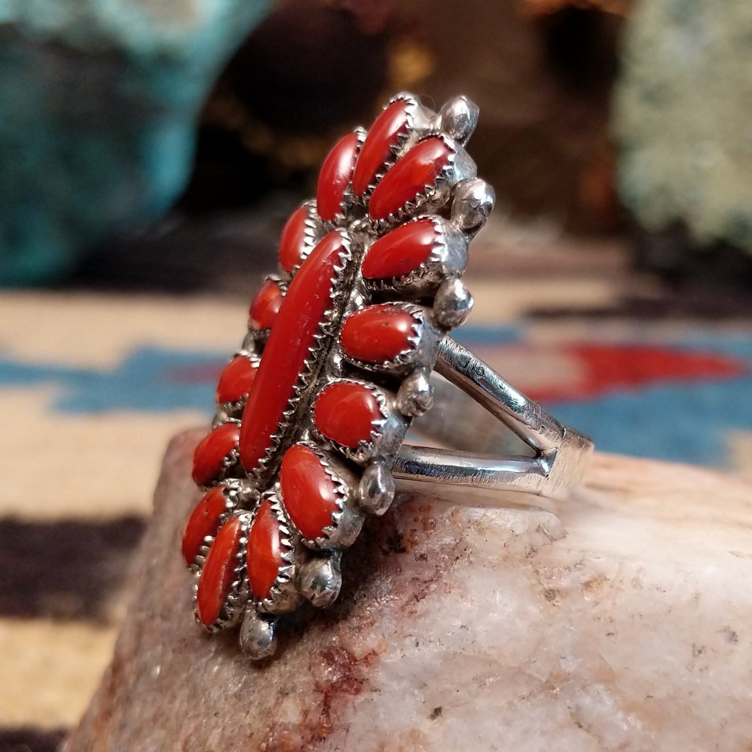 Sterling silver floral coral ring by Lorraine Waatsa featuring a vibrant red coral stone in a detailed Southwestern design.  Side view.