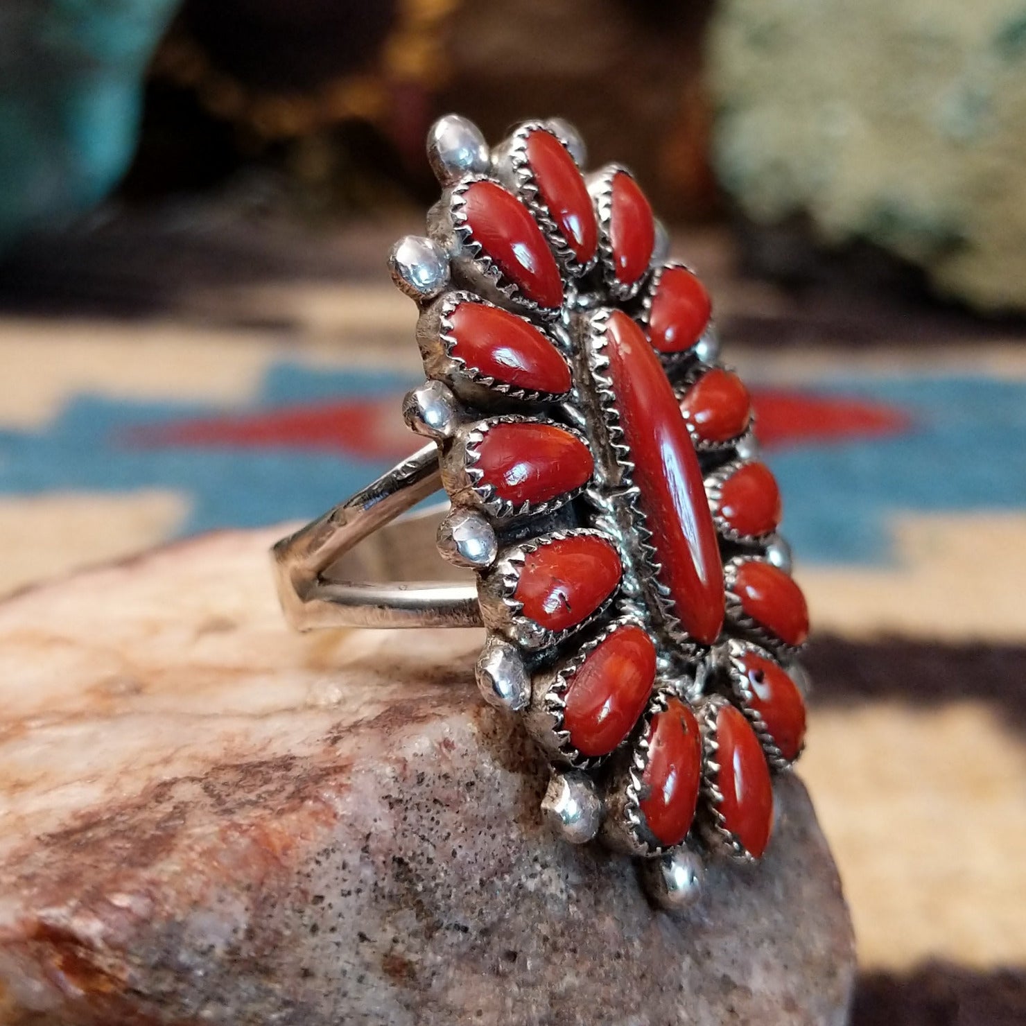 Sterling silver floral coral ring by Lorraine Waatsa featuring a vibrant red coral stone in a detailed Southwestern design.  Side view.