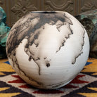 Medium globe-shaped white horsehair pottery vase by local artist Jim Calhoun featuring smoky organic patterns, a polished finish, and Southwestern handcrafted design.