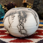 Small globe-shaped white horsehair pottery vase by local artisan Jim Calhoun featuring smoky organic markings, polished finish, and handcrafted Southwestern design.