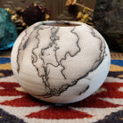 Small globe-shaped white horsehair pottery vase by local artisan Jim Calhoun featuring smoky organic markings, polished finish, and handcrafted Southwestern design.