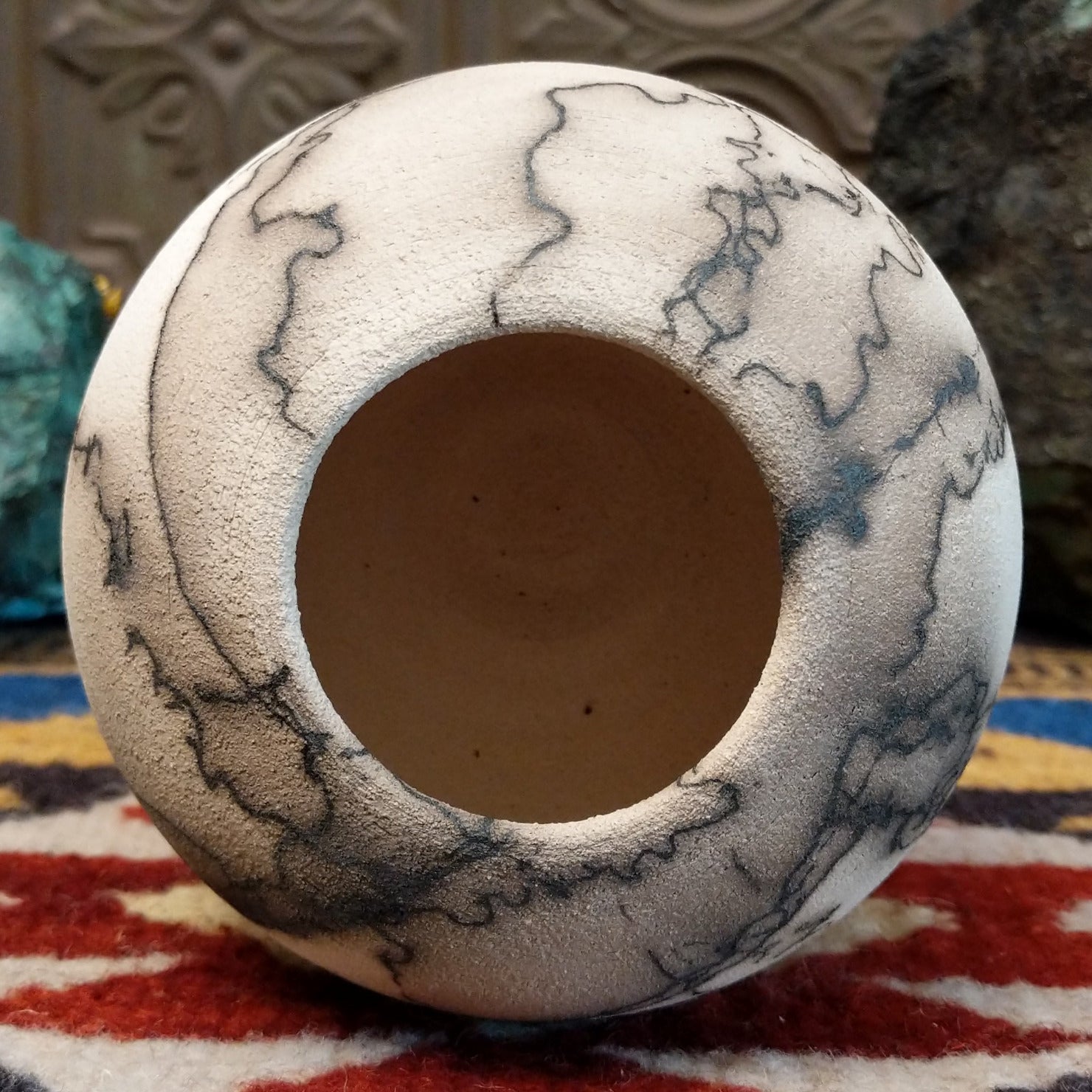 Small globe-shaped white horsehair pottery vase by local artisan Jim Calhoun featuring smoky organic markings, polished finish, and handcrafted Southwestern design.  Top view.