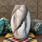Large oval-shaped white horsehair pottery vase by local artisan Jim Calhoun featuring bold black smoky patterns, polished white finish, and handcrafted Southwestern design.