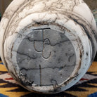 Large oval-shaped white horsehair pottery vase by local artisan Jim Calhoun featuring bold black smoky patterns, polished white finish, and handcrafted Southwestern design.  Underside view with artisan initials.