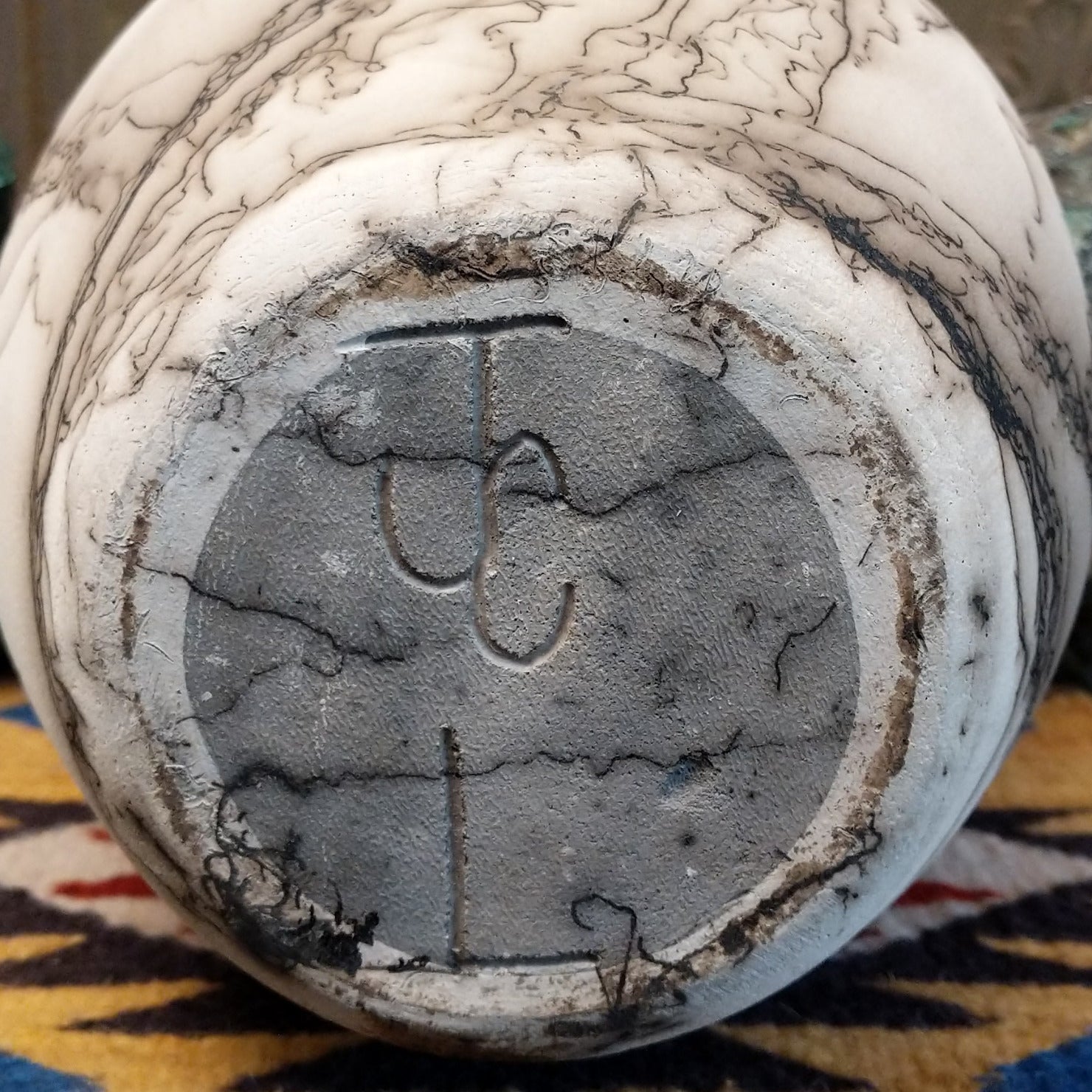Large oval-shaped white horsehair pottery vase by local artisan Jim Calhoun featuring bold black smoky patterns, polished white finish, and handcrafted Southwestern design.  Underside view with artisan initials.