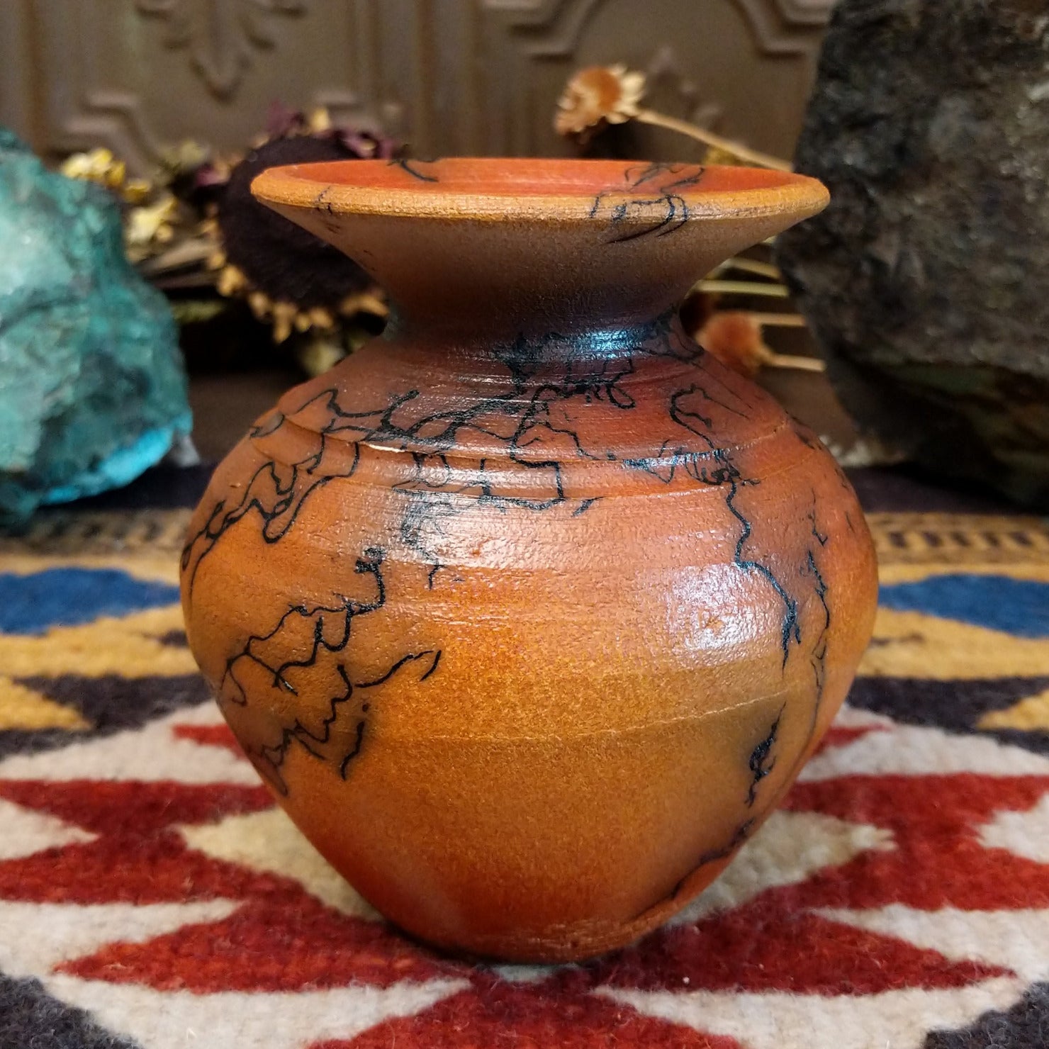 Small handcrafted terracotta horsehair vase with a rounded body and flared rim, decorated with black abstract horsehair firing patterns by artisan Jim Calhoun.