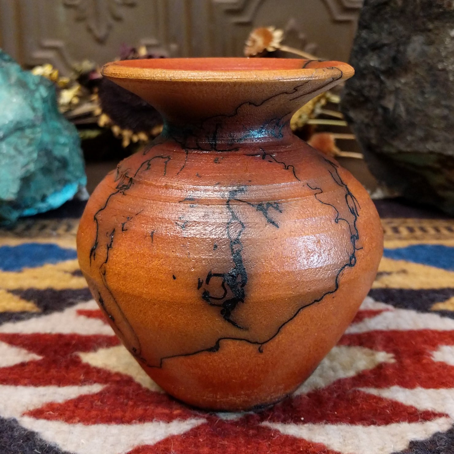 Small handcrafted terracotta horsehair vase with a rounded body and flared rim, decorated with black abstract horsehair firing patterns by artisan Jim Calhoun.