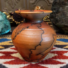 Small handcrafted terracotta horsehair vase with a rounded body and flared rim, decorated with black abstract horsehair firing patterns by artisan Jim Calhoun.