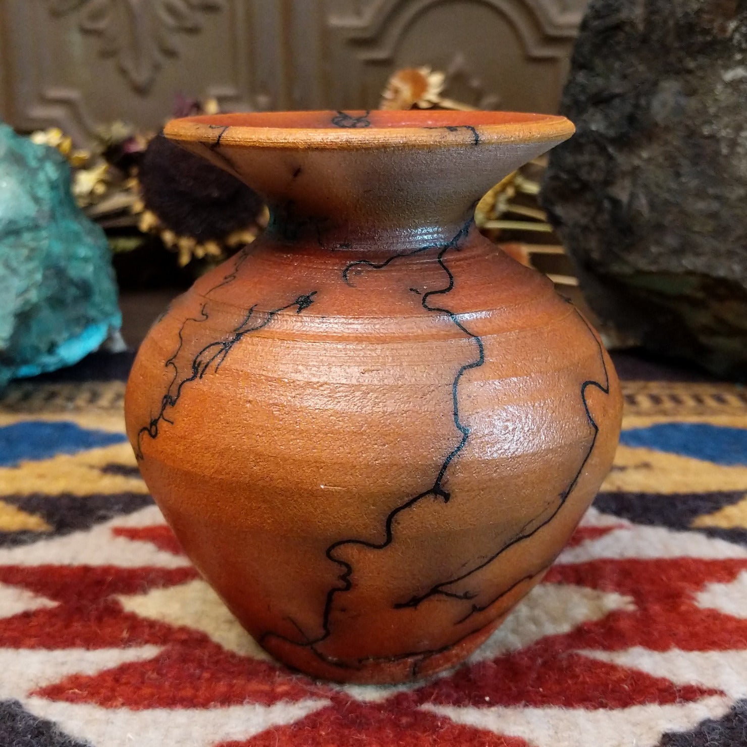 Small handcrafted terracotta horsehair vase with a rounded body and flared rim, decorated with black abstract horsehair firing patterns by artisan Jim Calhoun.