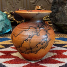 Small handcrafted terracotta horsehair vase with a rounded body and flared rim, decorated with black abstract horsehair firing patterns by artisan Jim Calhoun.