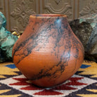 Medium-sized handcrafted terracotta horsehair pot with a rounded shape and flared opening, featuring black organic horsehair firing patterns on a warm terracotta finish by artisan Jim Calhoun.