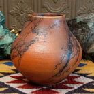 Medium-sized handcrafted terracotta horsehair pot with a rounded shape and flared opening, featuring black organic horsehair firing patterns on a warm terracotta finish by artisan Jim Calhoun.