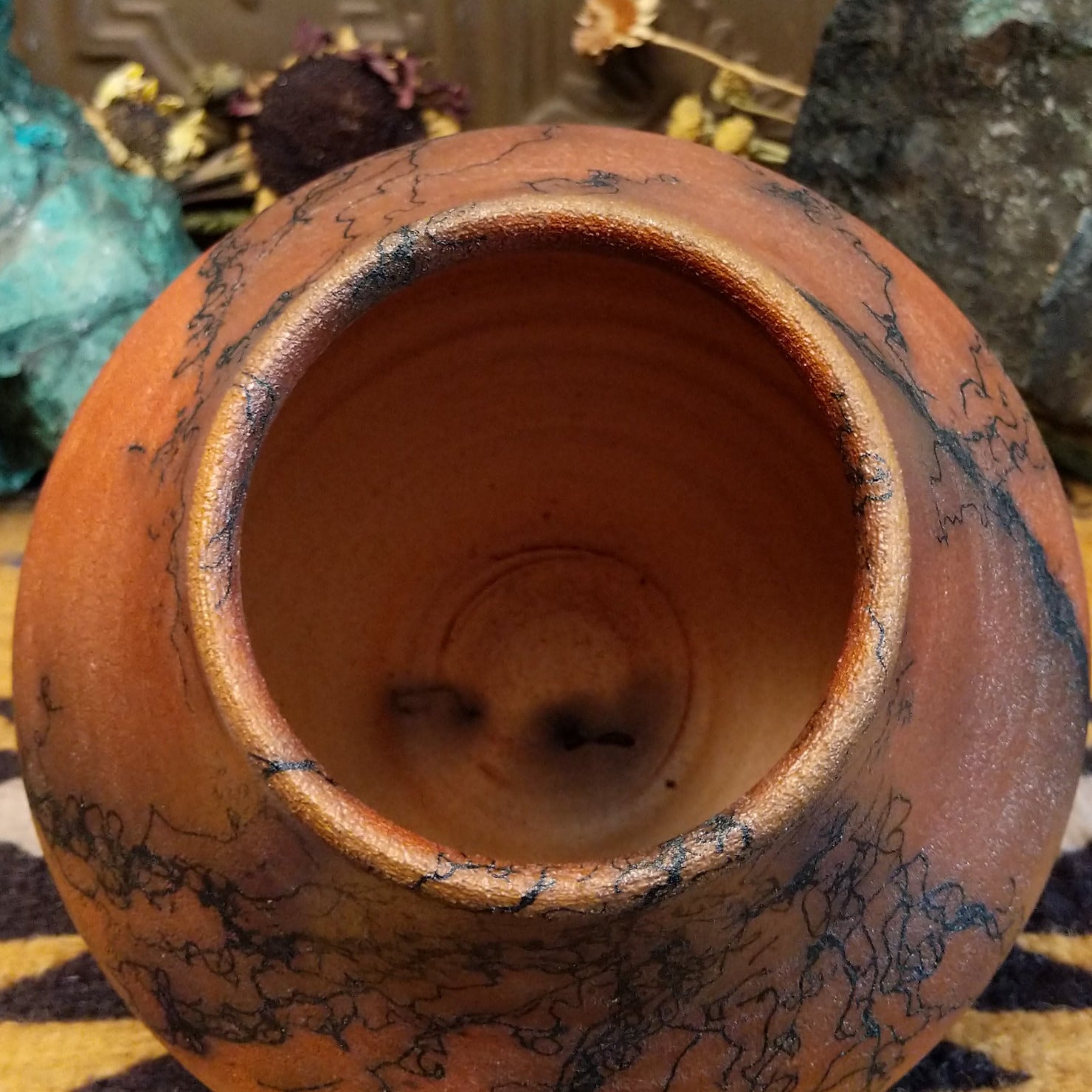 Medium-sized handcrafted terracotta horsehair pot with a rounded shape and flared opening, featuring black organic horsehair firing patterns on a warm terracotta finish by artisan Jim Calhoun.  Top view.
