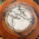 Medium-sized handcrafted terracotta horsehair pot with a rounded shape and flared opening, featuring black organic horsehair firing patterns on a warm terracotta finish by artisan Jim Calhoun.  Underside view with artisan initials.