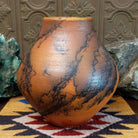Large terracotta horsehair pottery vase by local artisan Jim Calhoun with rounded shape, warm clay tones, and distinctive black horsehair fire patterns across the surface.