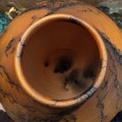 Large terracotta horsehair pottery vase by local artisan Jim Calhoun with rounded shape, warm clay tones, and distinctive black horsehair fire patterns across the surface.  Top view.