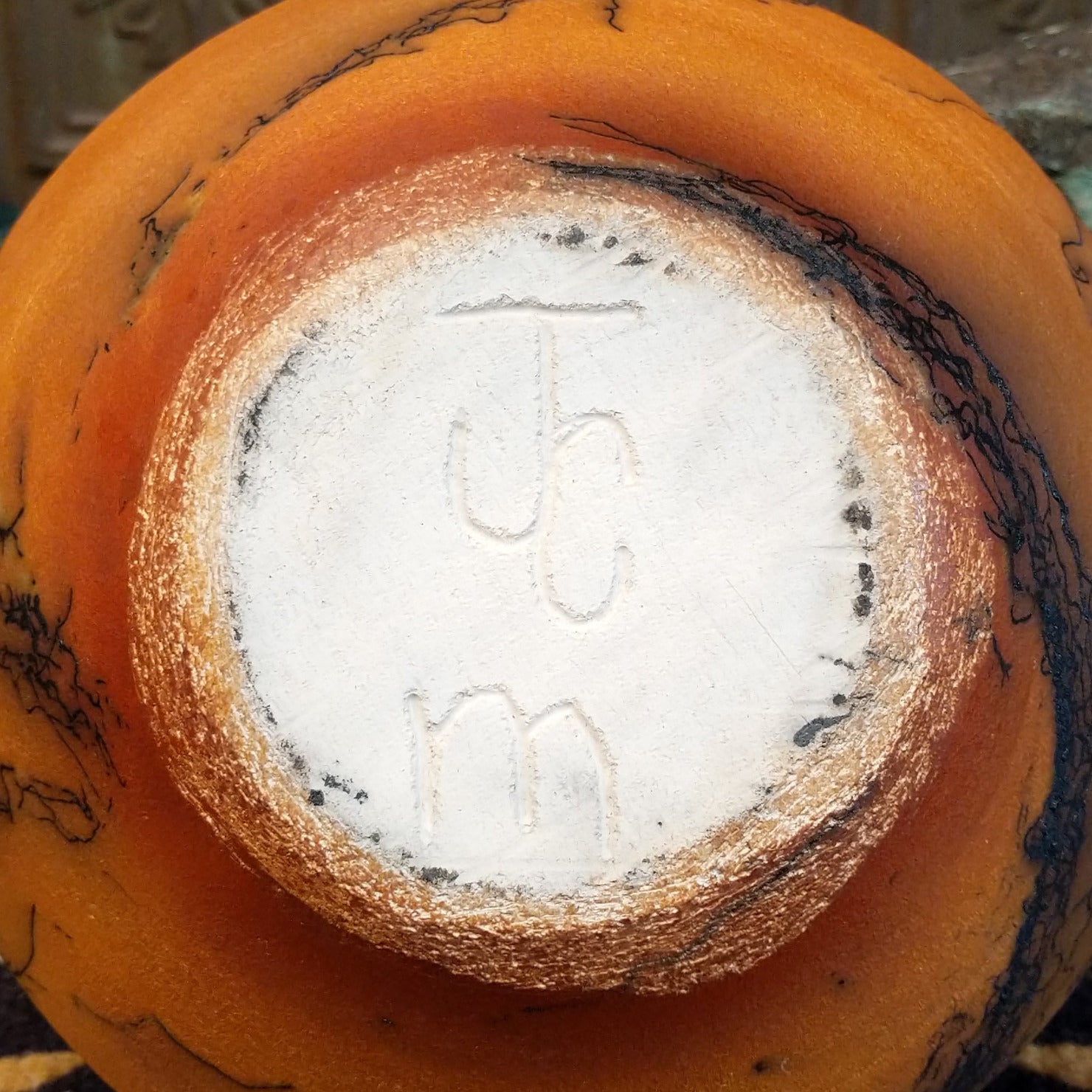 Large terracotta horsehair pottery vase by local artisan Jim Calhoun with rounded shape, warm clay tones, and distinctive black horsehair fire patterns across the surface.  Underside view with artisan initials.