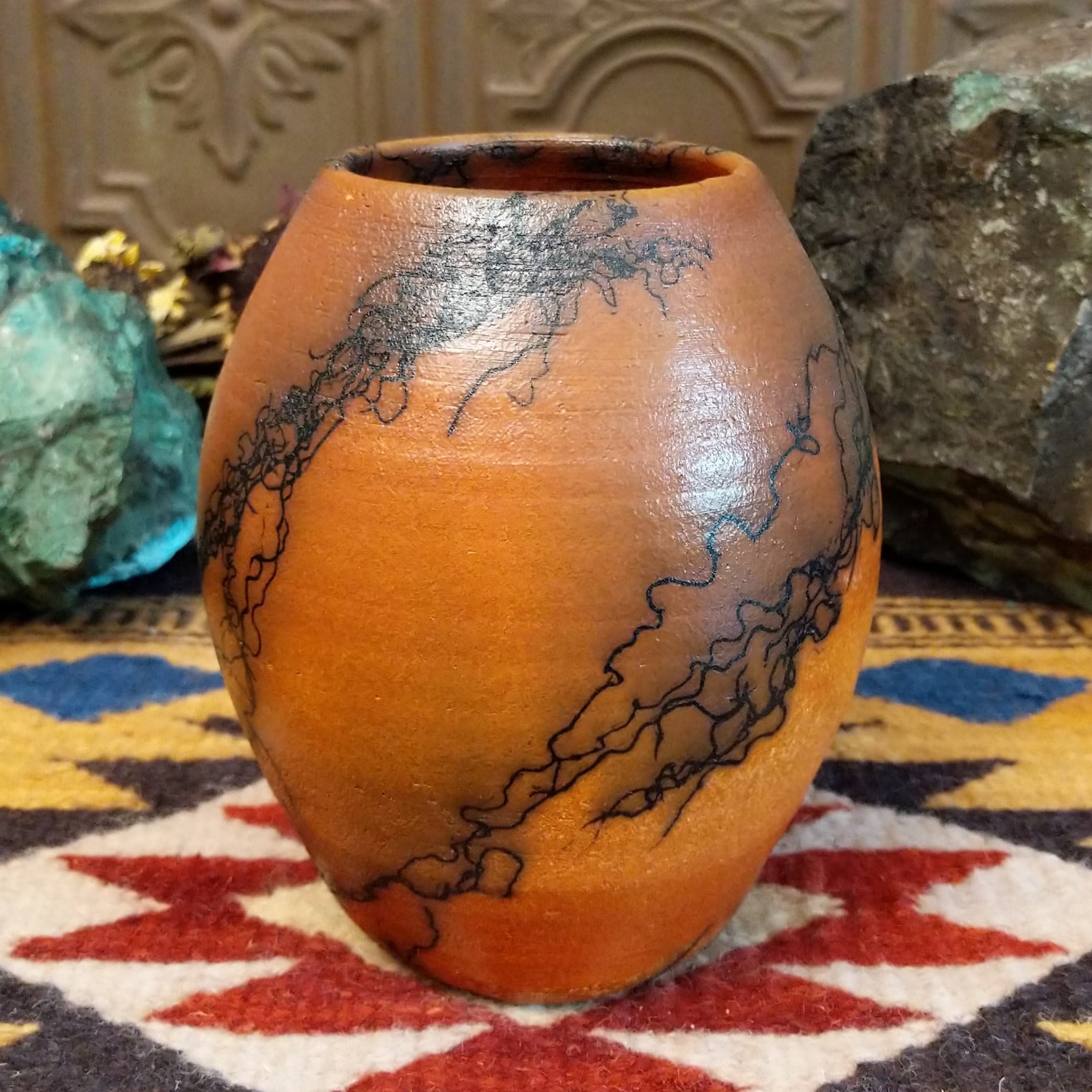 Small oval terracotta horsehair vase handcrafted by local artisan Jim Calhoun, featuring warm earthy clay tones and delicate black horsehair fire patterns on a smooth rounded surface.