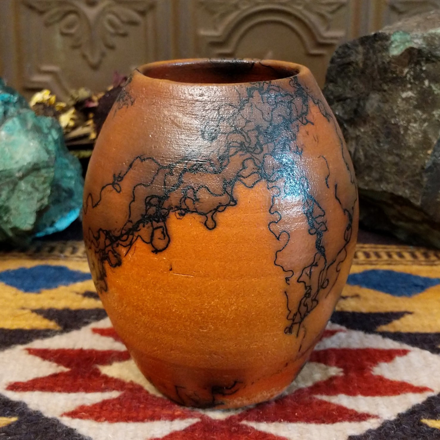 Small oval terracotta horsehair vase handcrafted by local artisan Jim Calhoun, featuring warm earthy clay tones and delicate black horsehair fire patterns on a smooth rounded surface.