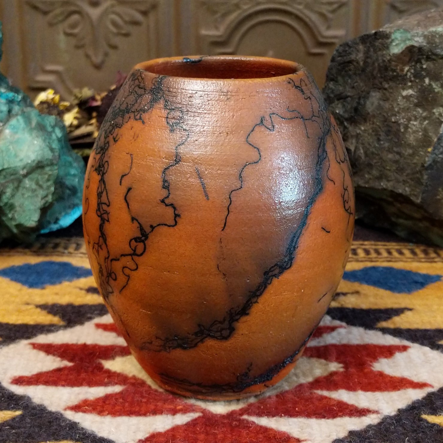 Small oval terracotta horsehair vase handcrafted by local artisan Jim Calhoun, featuring warm earthy clay tones and delicate black horsehair fire patterns on a smooth rounded surface.