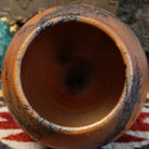 Small oval terracotta horsehair vase handcrafted by local artisan Jim Calhoun, featuring warm earthy clay tones and delicate black horsehair fire patterns on a smooth rounded surface.  Top view.