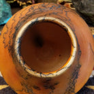 Small terracotta horsehair pot handcrafted by local artisan Jim Calhoun, featuring earthy clay tones and unique black horsehair fire patterns on a rounded pottery form.  Top view.