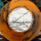 Small terracotta horsehair pot handcrafted by local artisan Jim Calhoun, featuring earthy clay tones and unique black horsehair fire patterns on a rounded pottery form.  Underside view with artisan initials.