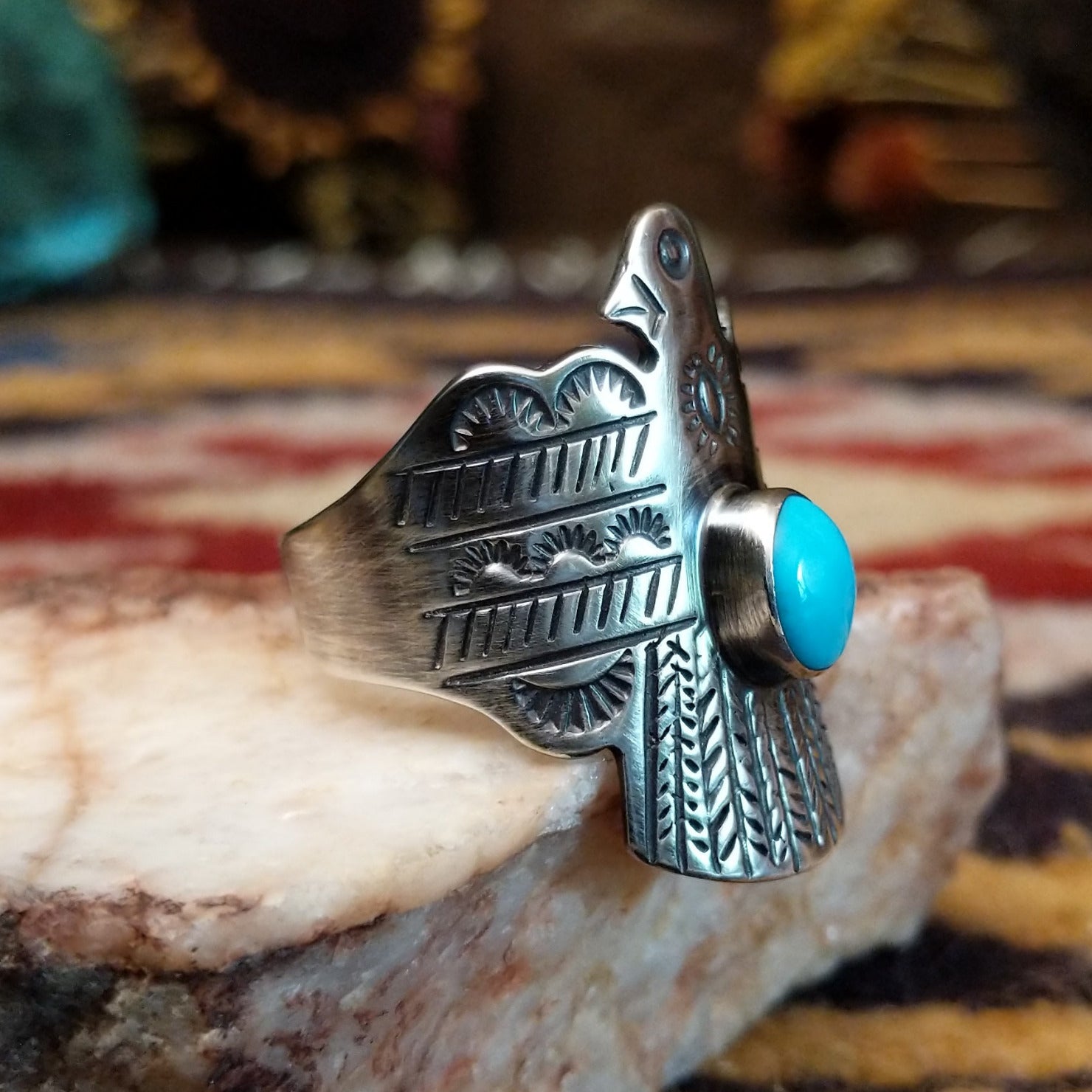 Handcrafted sterling silver Thunderbird ring by Raymond Coriz featuring a turquoise stone and traditional Southwestern Native American design details.  Side view.