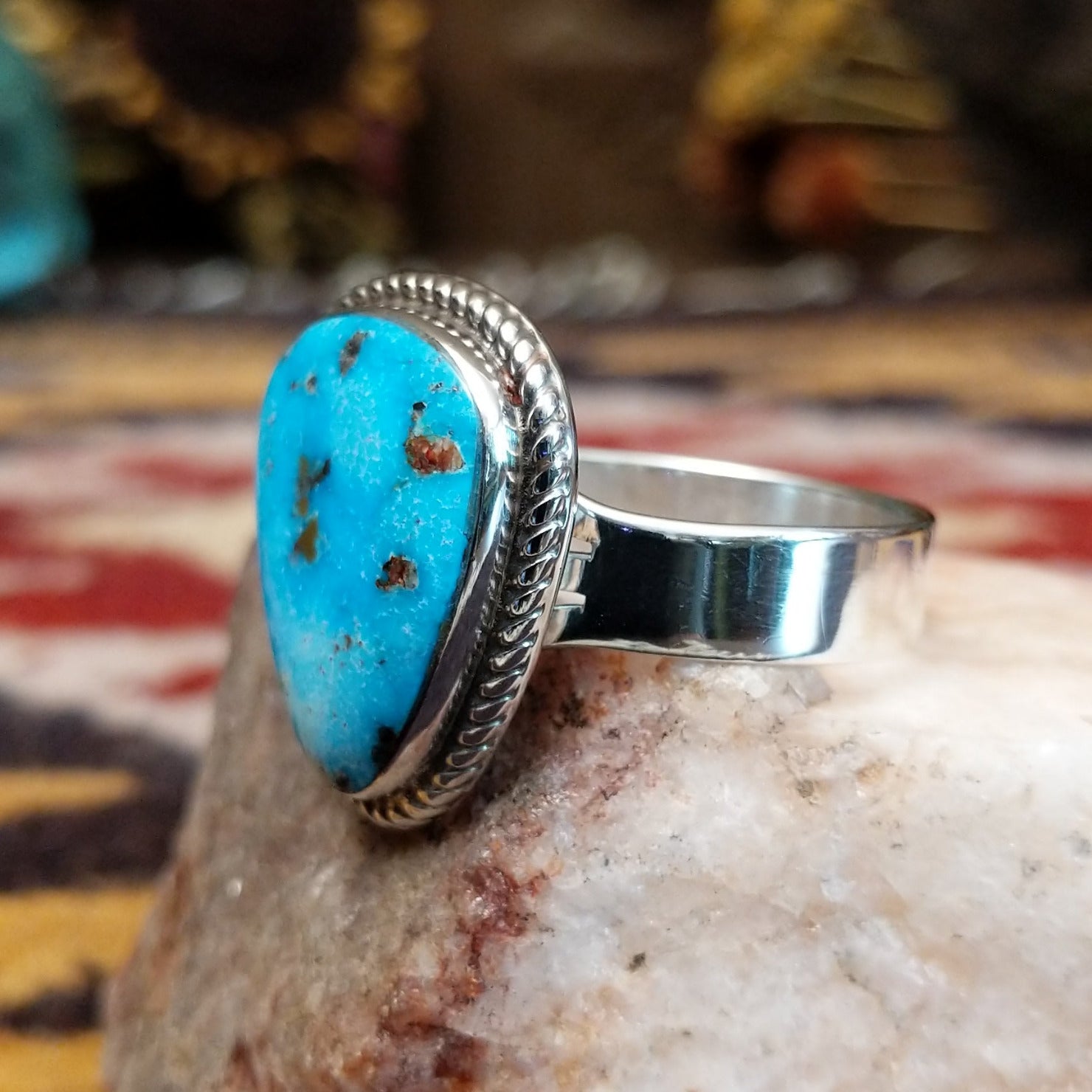 Handcrafted sterling silver ring by S.R. Chee featuring a triangular turquoise stone with traditional Southwestern Native American silver detailing.  Side view.