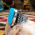 Handcrafted Navajo sterling silver ring by L.J. featuring a turquoise stone with traditional stamped silver detailing in a Southwestern design.  Side view.