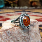 Handcrafted sterling silver ring by Artie Yellowhorse featuring a warm amber stone in a polished Southwestern Native American design.  Side view.