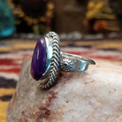 Handcrafted sterling silver ovoid ring by Artie Yellowhorse featuring a deep purple sugilite stone in a polished Southwestern Native American design.  Side view.