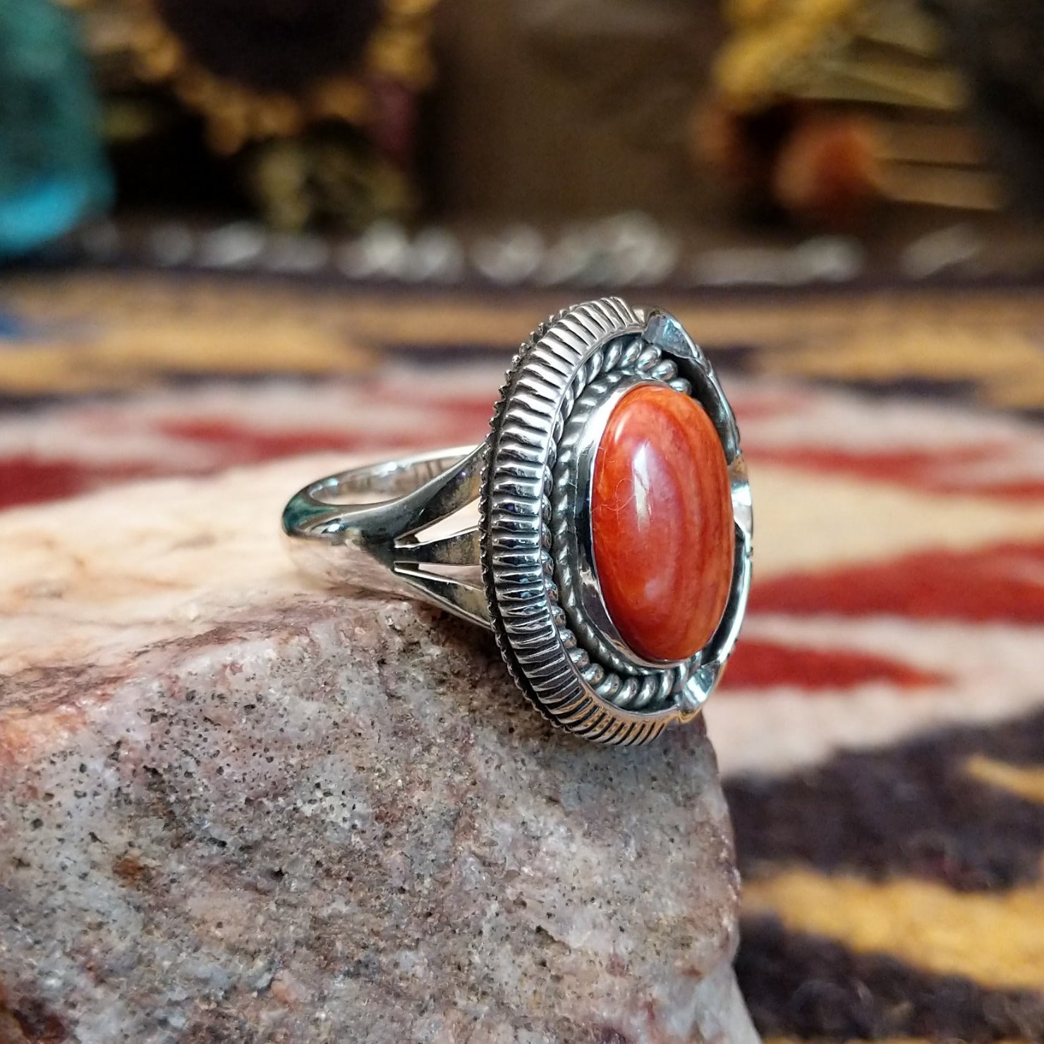 Handcrafted sterling silver oval ring by Artie Yellowhorse featuring a red spiny oyster shell in a polished Southwestern Native American design.  Side view.