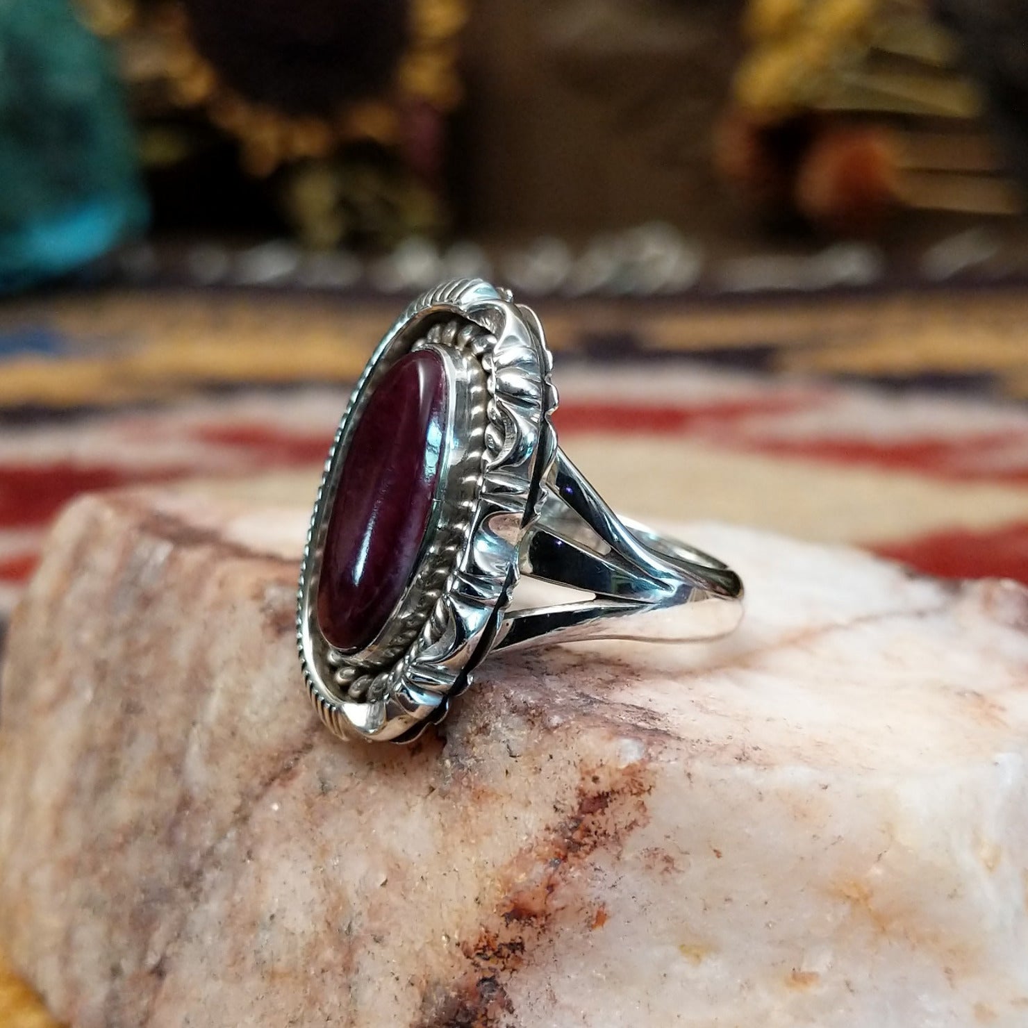 Handcrafted sterling silver ellipse ring by Artie Yellowhorse featuring a purple spiny oyster shell in a polished Southwestern Native American design.  Side view.