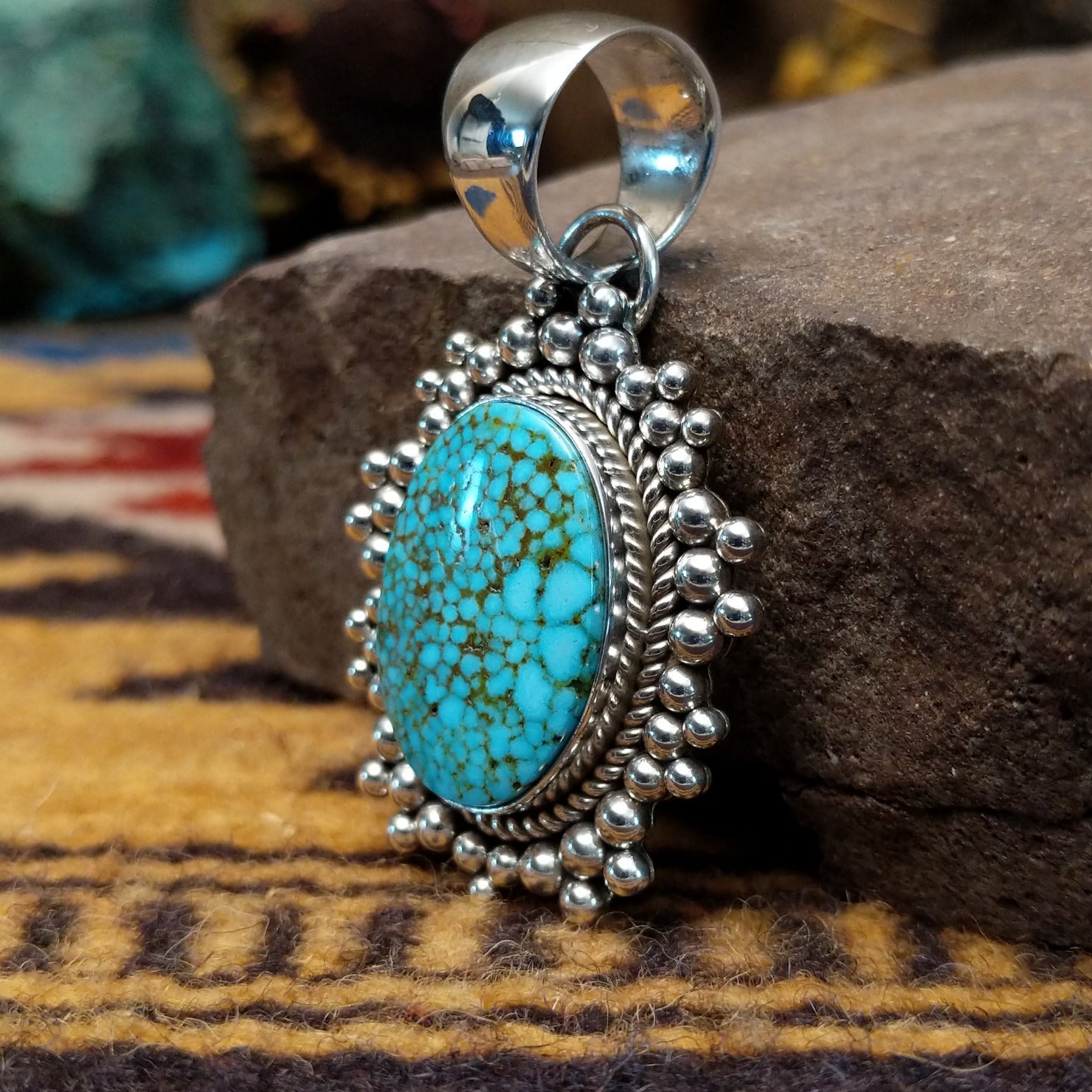 Handcrafted sterling silver pendant by Artie Yellowhorse featuring a Kingman turquoise stone in a polished Southwestern Native American design.  Side view.