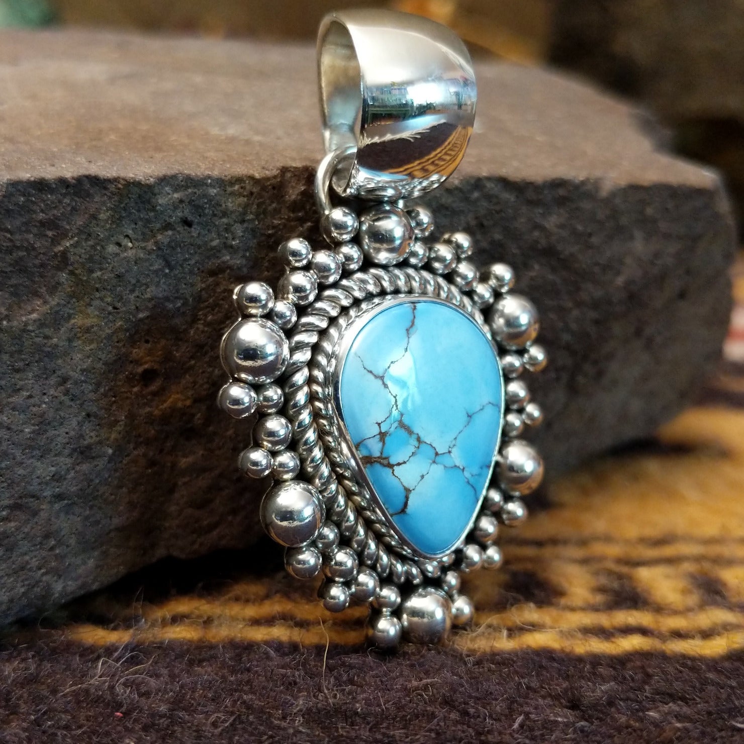 Handcrafted sterling silver pendant by Artie Yellowhorse featuring a Golden Hills turquoise stone in a polished Southwestern Native American design.  Side view.