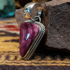Handcrafted sterling silver pendant by Artie Yellowhorse featuring a purple spiny oyster shell in a triangular Southwestern Native American design.  Side view.