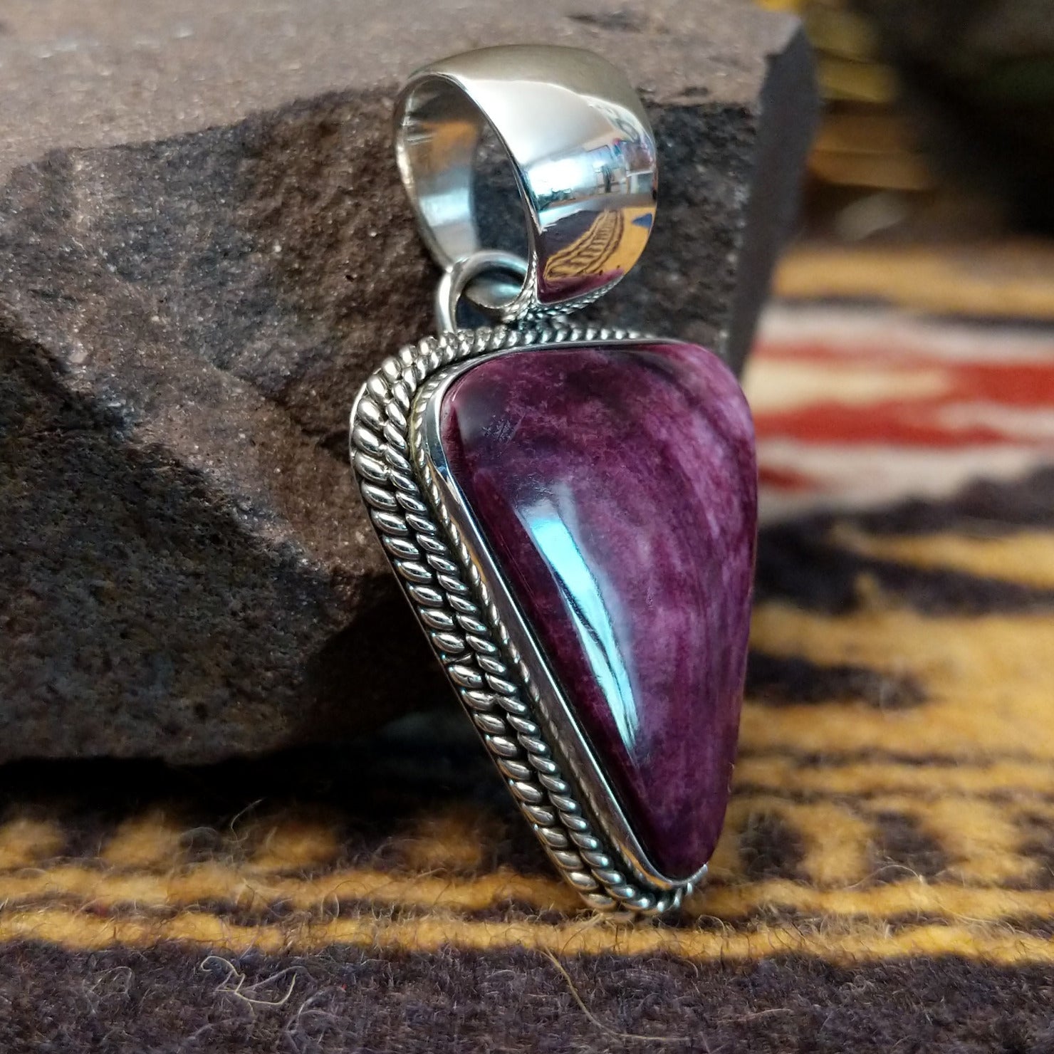 Handcrafted sterling silver pendant by Artie Yellowhorse featuring a purple spiny oyster shell in a triangular Southwestern Native American design.  Side view.