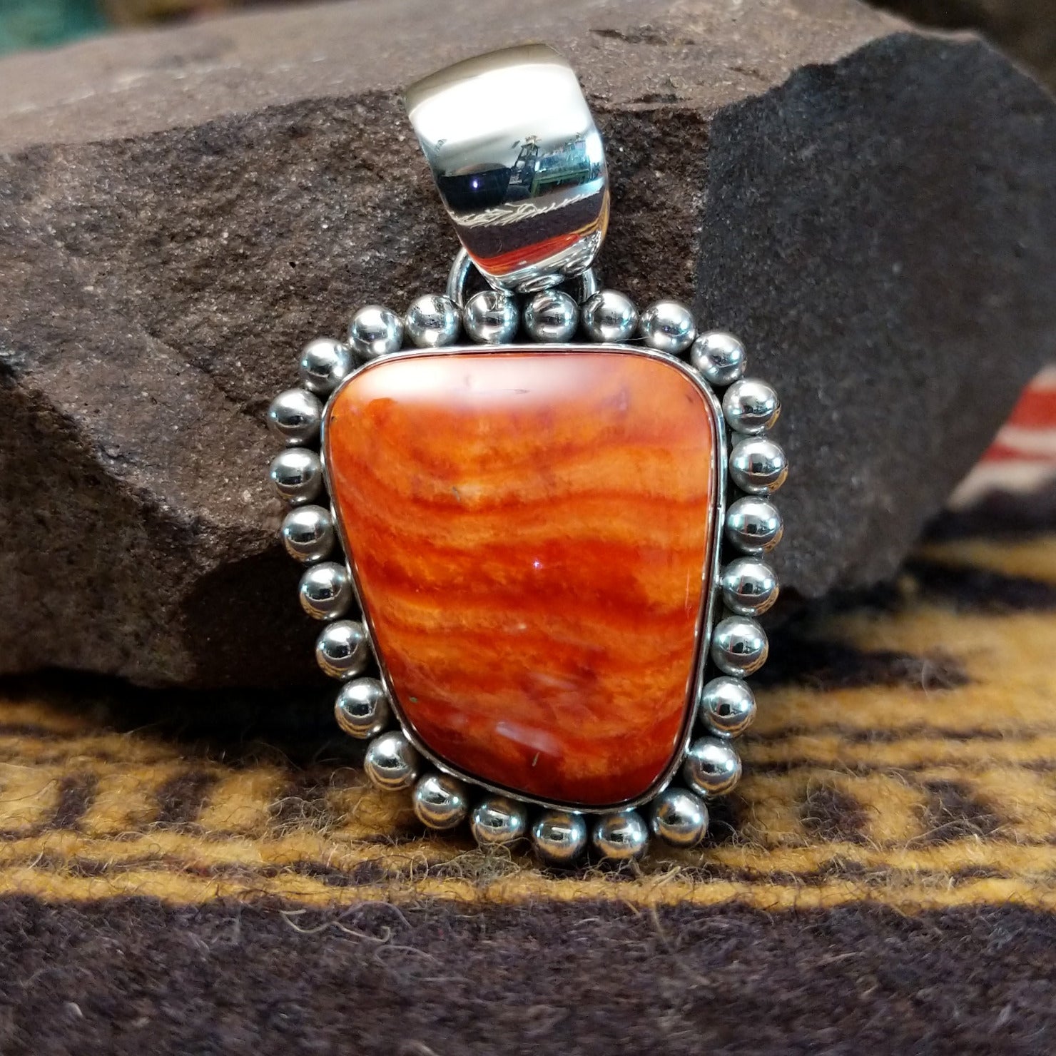 Handcrafted sterling silver pendant by Artie Yellowhorse featuring a red spiny oyster shell with dotted silver detailing in a Southwestern Native American design.