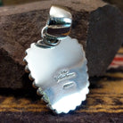 Handcrafted sterling silver pendant by Artie Yellowhorse featuring a red spiny oyster shell with dotted silver detailing in a Southwestern Native American design.  Back view showcasing artisan and Sterling Silver stamp.
