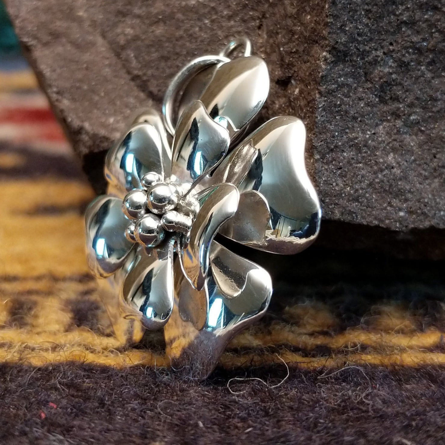Handcrafted sterling silver pendant by Artie Yellowhorse featuring a detailed dogwood flower design in a polished Southwestern Native American style.  Side view.