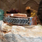 Handcrafted copper and sterling silver cuff bracelet by Robert Little featuring chevron-stamped detailing in a traditional Southwestern Native American design.  Side view.